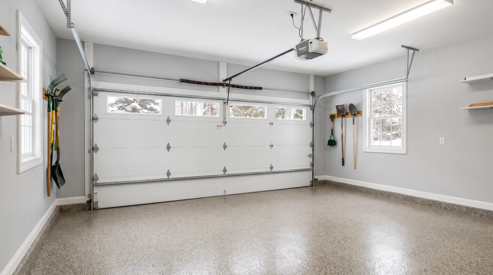 Attached two-car garage with a white insulated door, a torsion spring above it and a belt-drive opener on the ceiling
